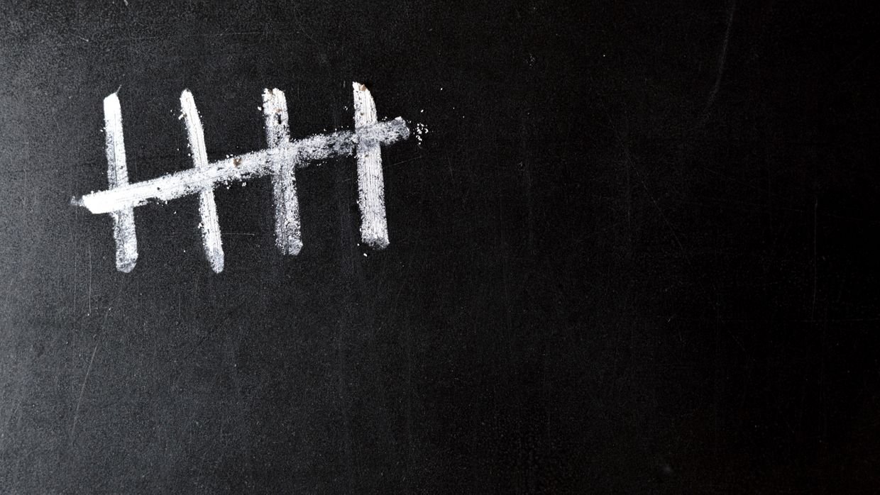 The number five chalked onto a board.