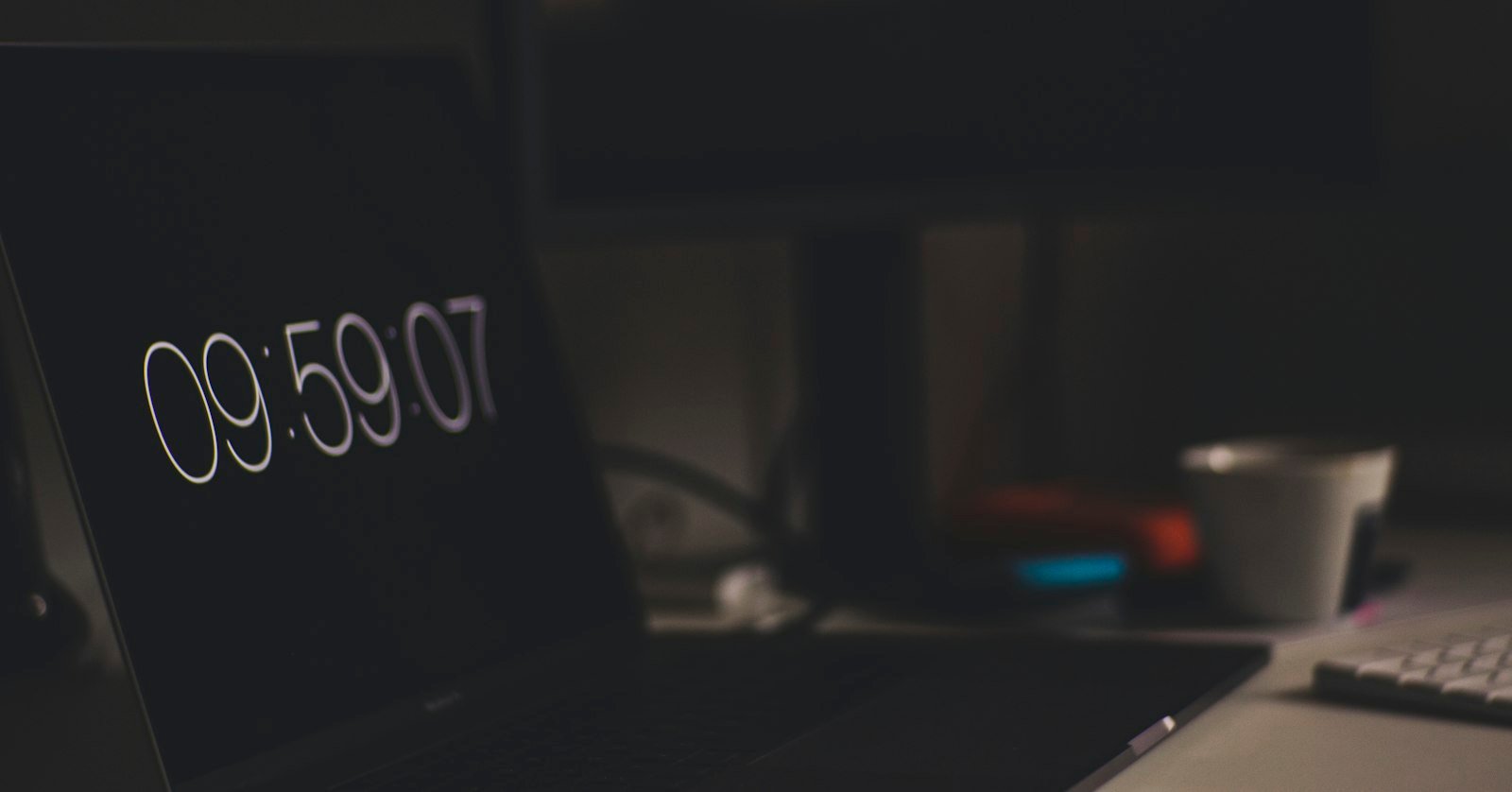 A clock face standing beside a laptop.