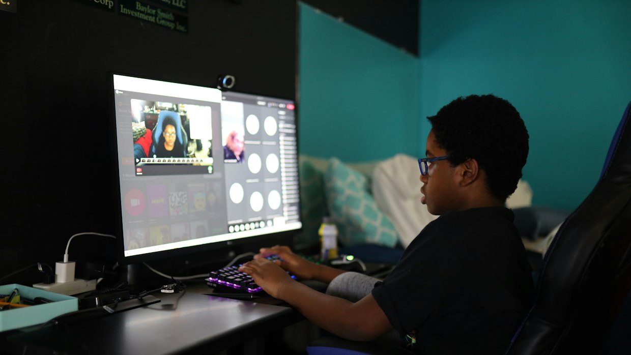 A student watching a recorded tutorial, lit only by the screen.