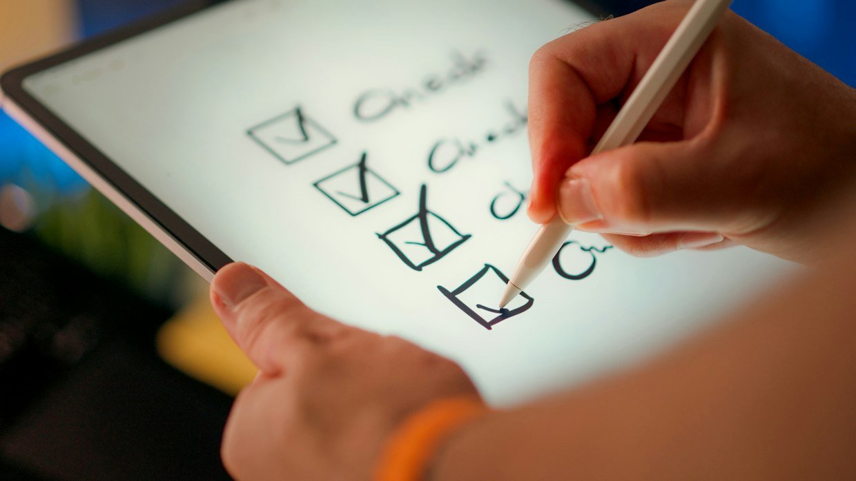 A checklist on a clipboard with boxes being ticked off.