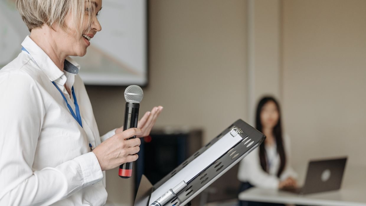 A speaker mid-sentence in front of a conference audience.