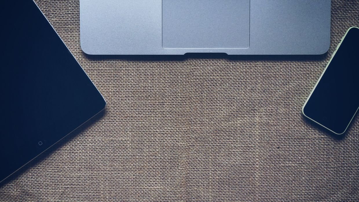A laptop, tablet and phone on a desk, for comparing three ways to summarize a video.