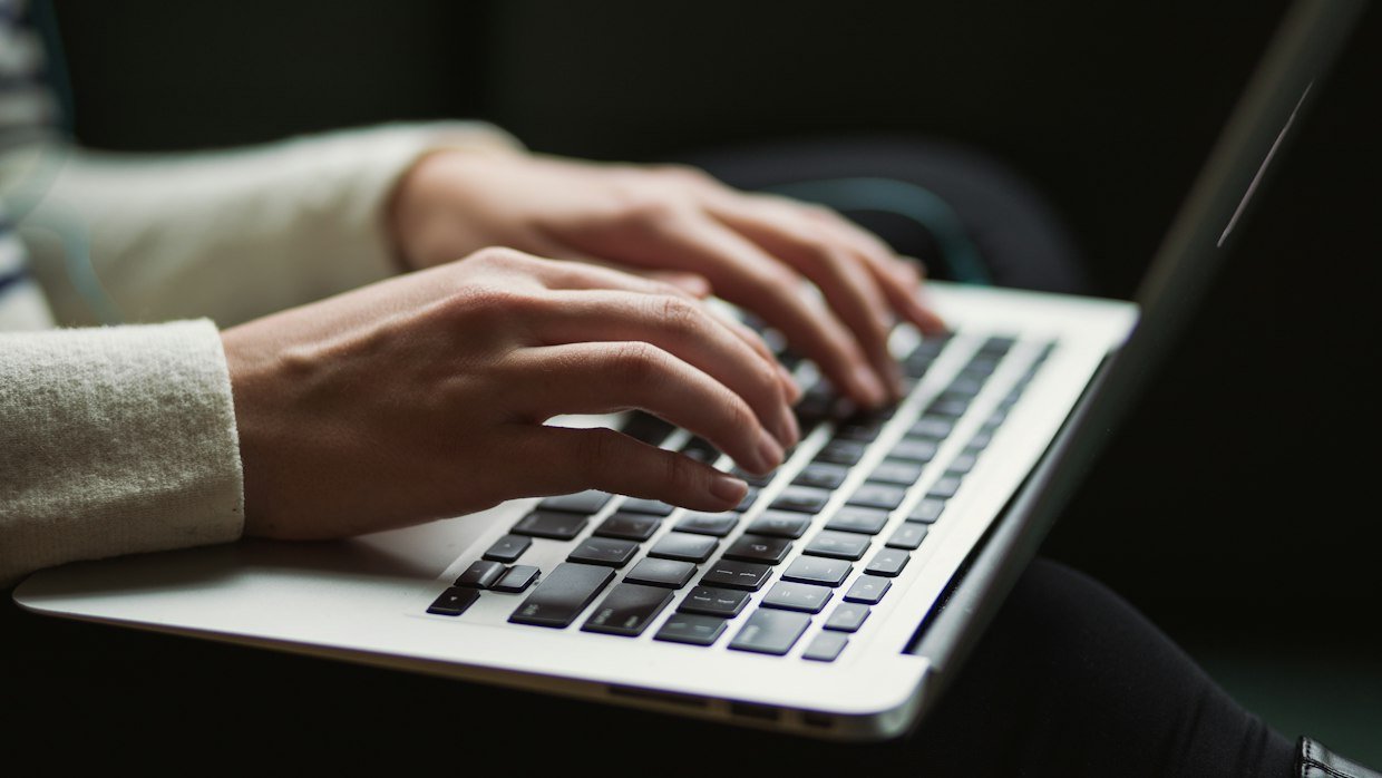 Hands typing a question on a laptop keyboard, for asking an assistant to summarize a video.