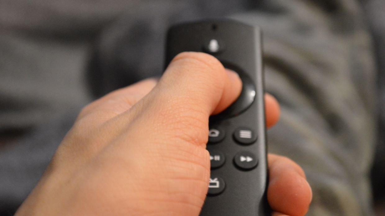 A hand holding a remote control, like switching closed captions on and off.