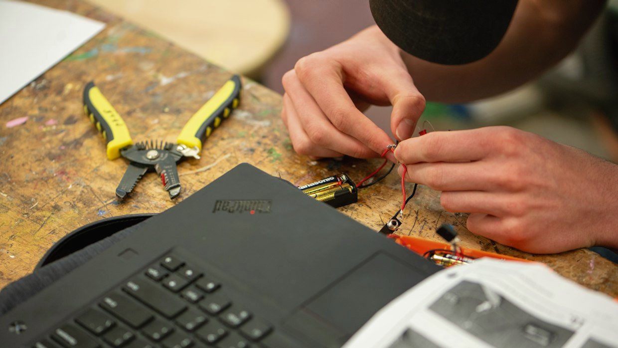 Hands using tools at a workbench.