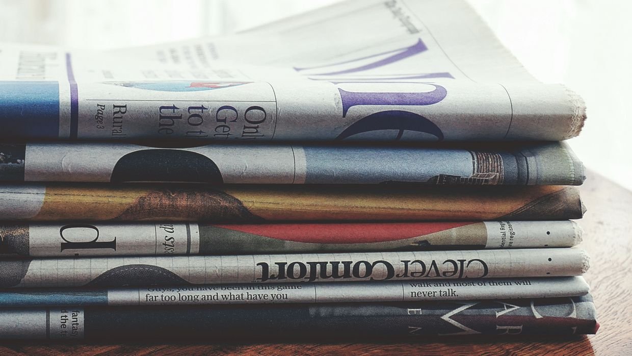 A stack of newspapers with visible dates.