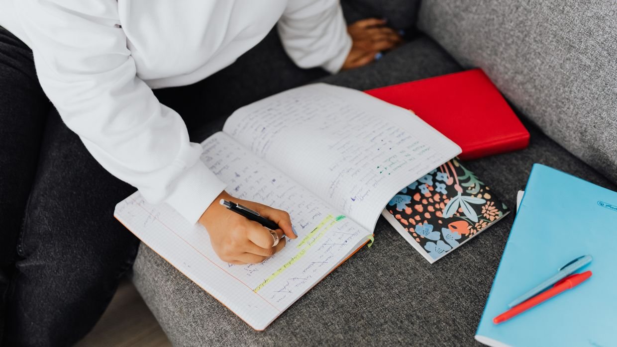A student covering part of a notebook to test recall, as in the Recite step.