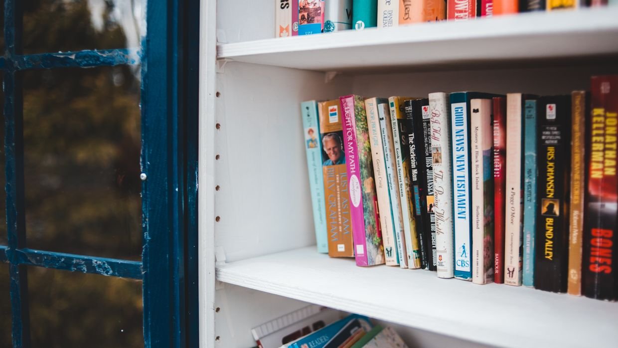 Books of varying sizes lined up on a shelf.