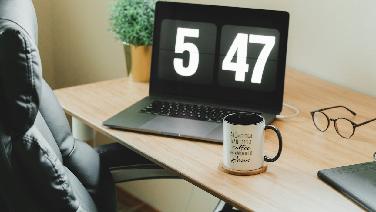 A stopwatch resting on a desk next to a laptop.