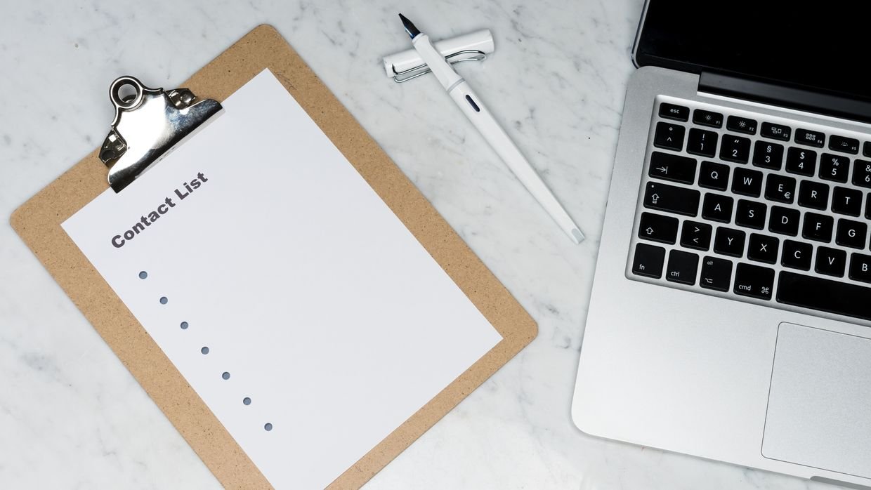 A clipboard next to an open laptop.