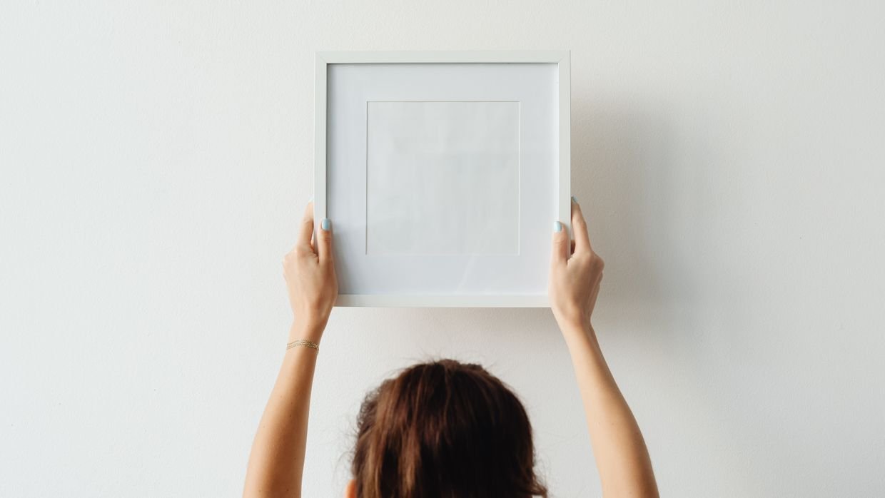 An empty picture frame hanging on a wall.