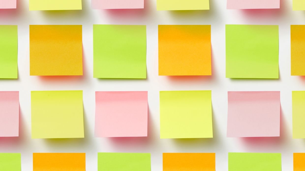 Sticky notes lined up in a column on a wall.
