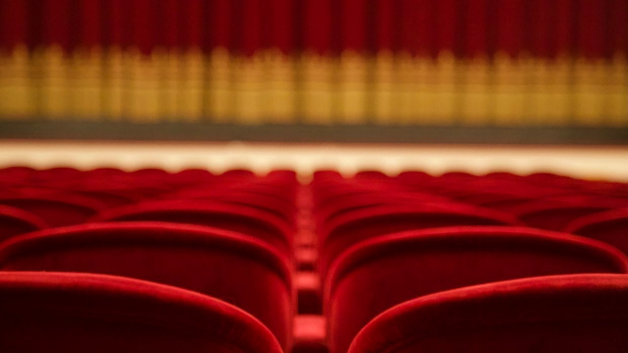 A row of empty chairs arranged on a stage.