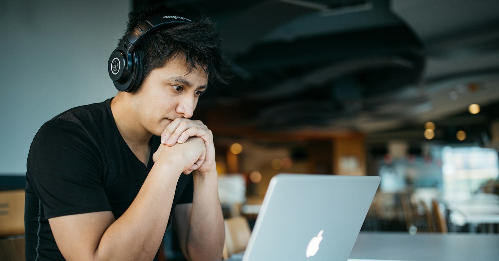 A learner with headphones watching a video and writing down what they understood.