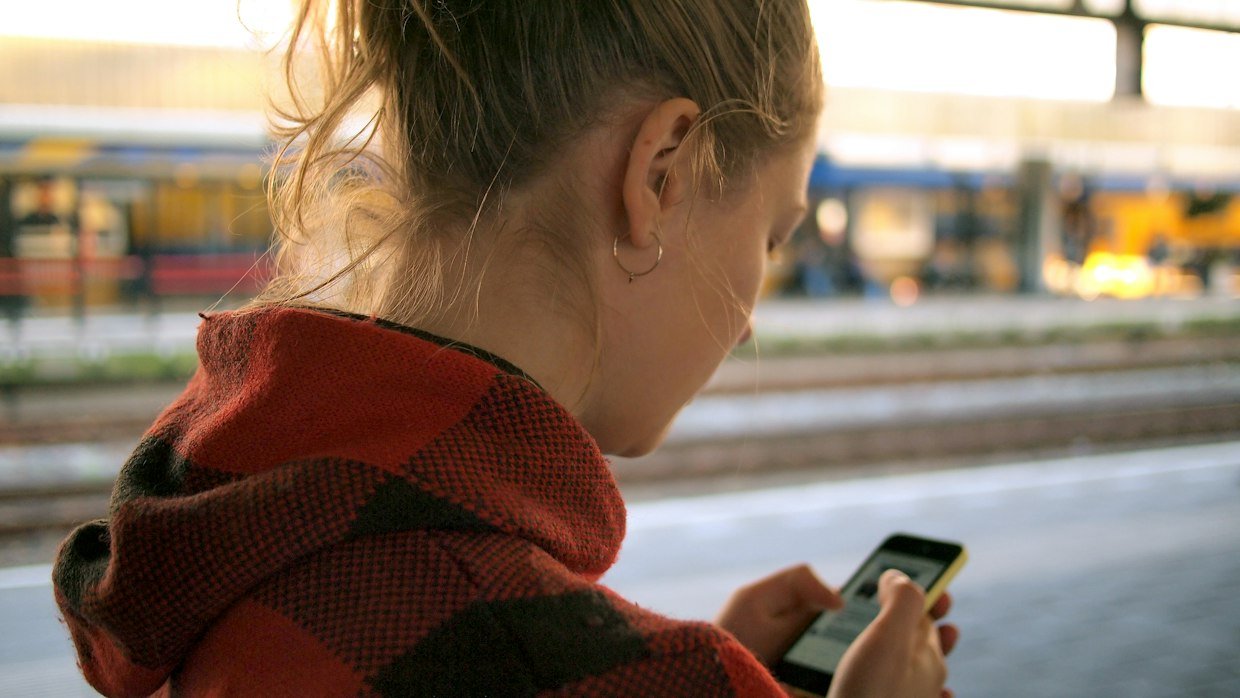 A commuter reading on a phone, where a short summary beats scrolling a transcript.