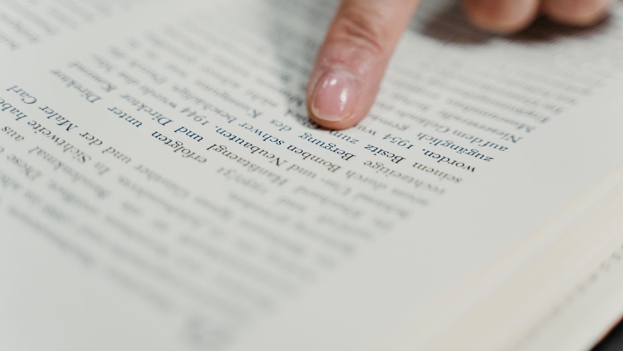 A finger resting on a line of printed text.