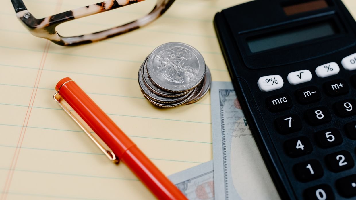 Small stacks of coins next to a notebook.