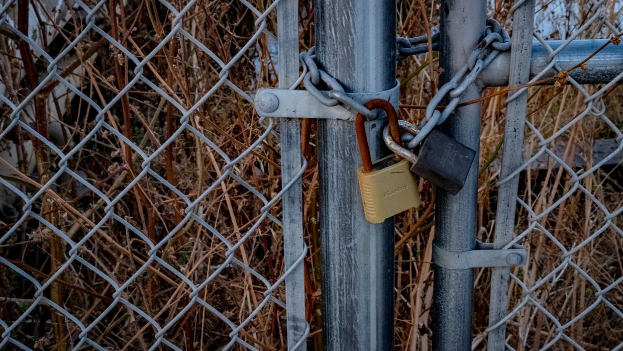 A padlock fastened to a chain link fence.