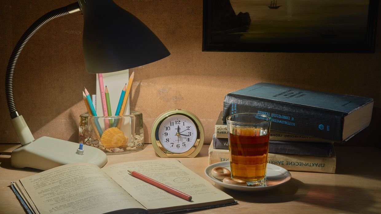 A study desk with stacked books and a lamp.