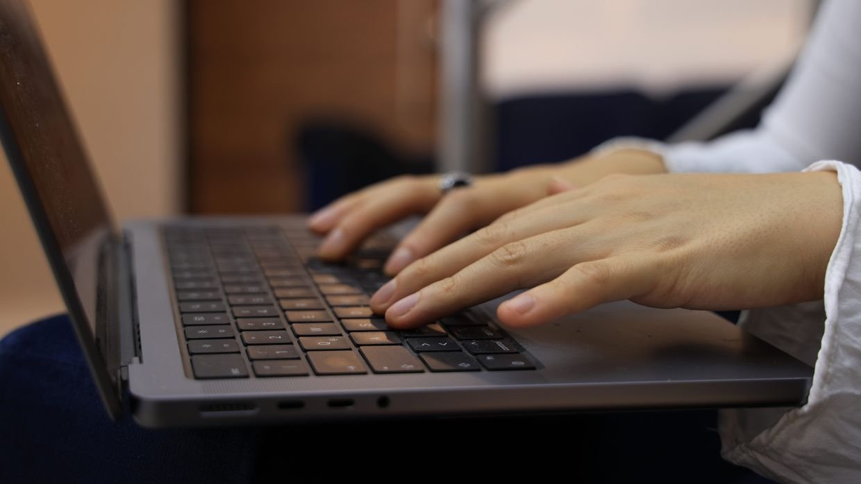 Hands typing on a laptop keyboard.