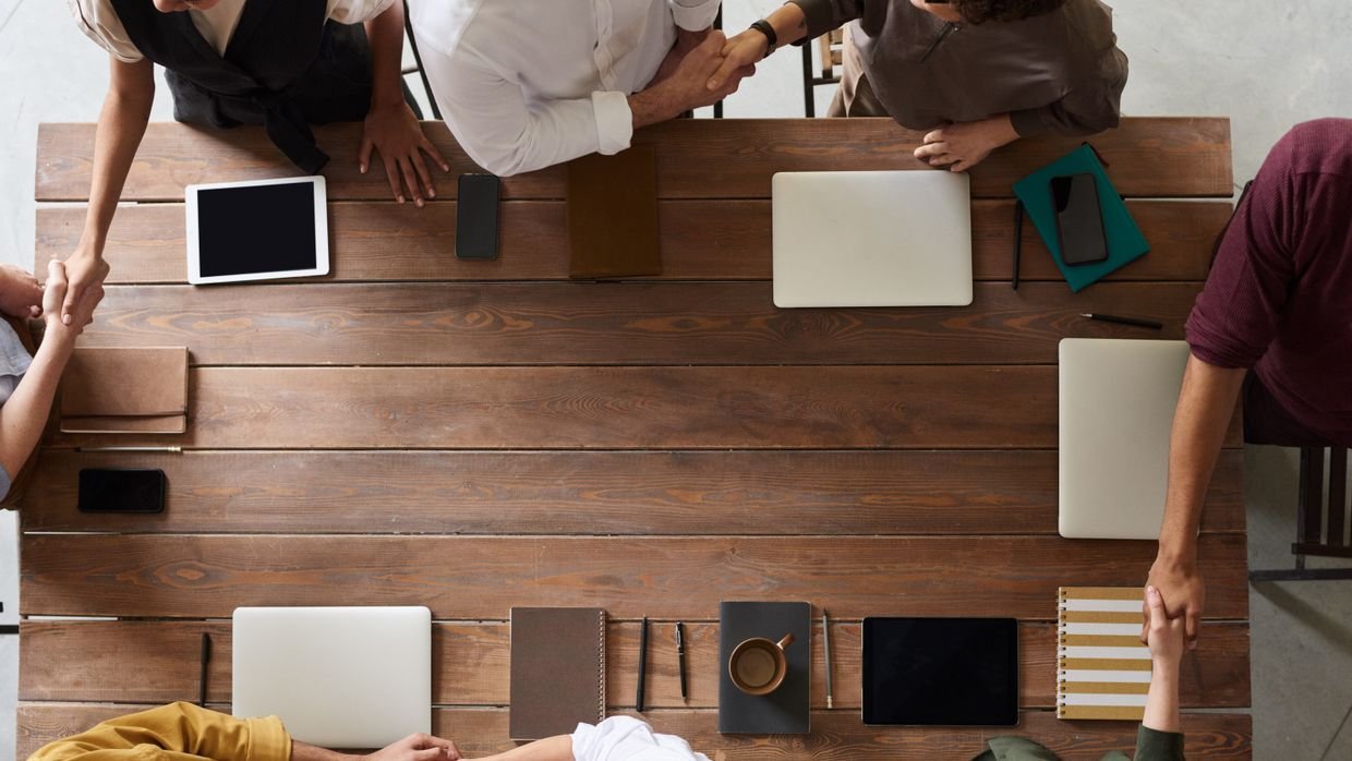 Two people shaking hands over a table.