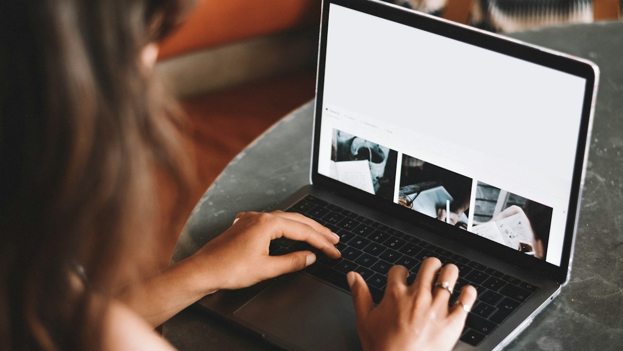A person watching a video on a laptop with notes beside it, for asking Opera AI about a video.