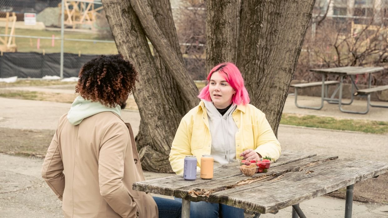 Two people talking across a table with microphones.