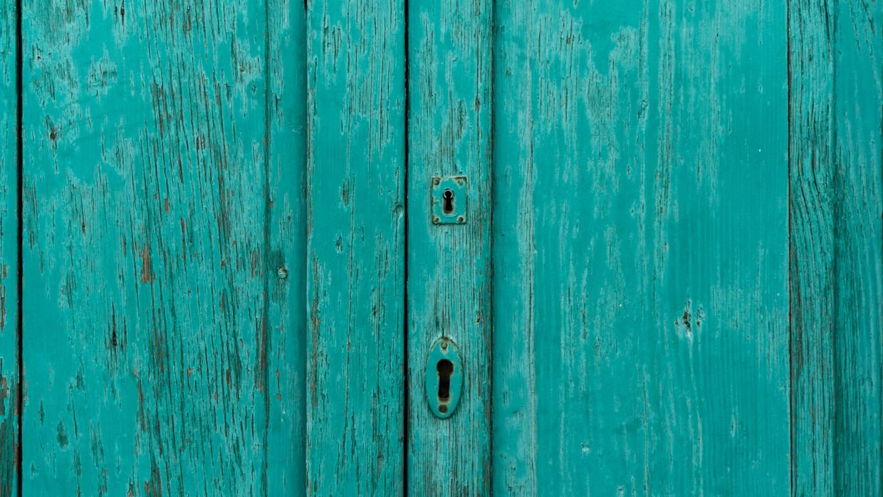 A keyhole in a wooden door.