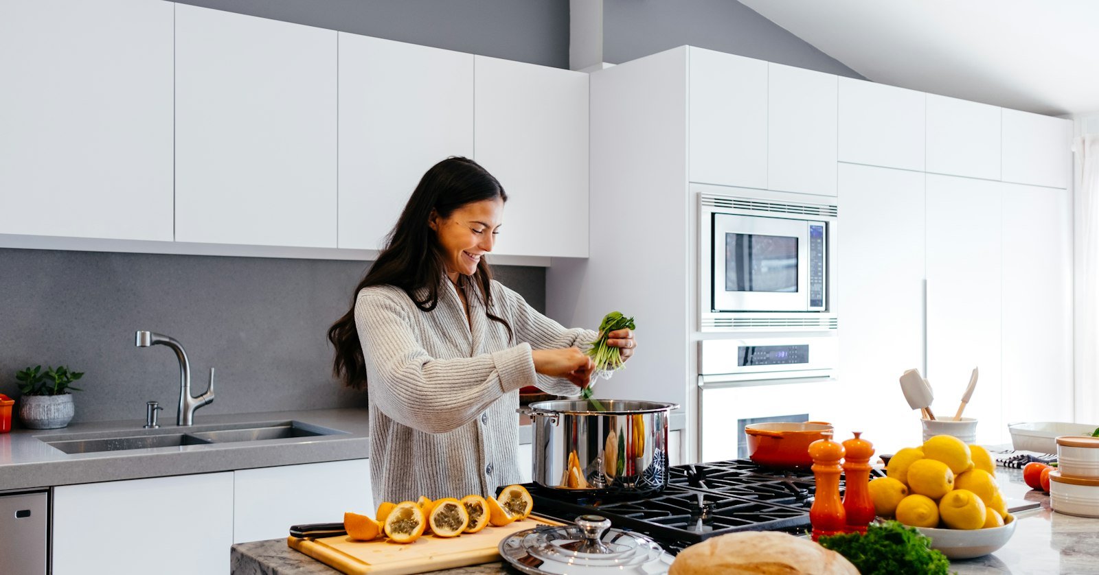 A home cook following a recipe video on a phone propped up beside the stove.