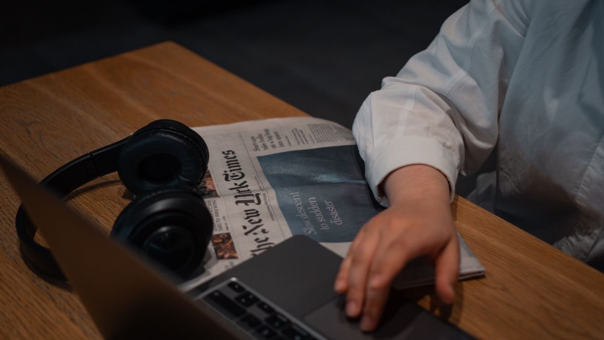 A newspaper lying beside a laptop.