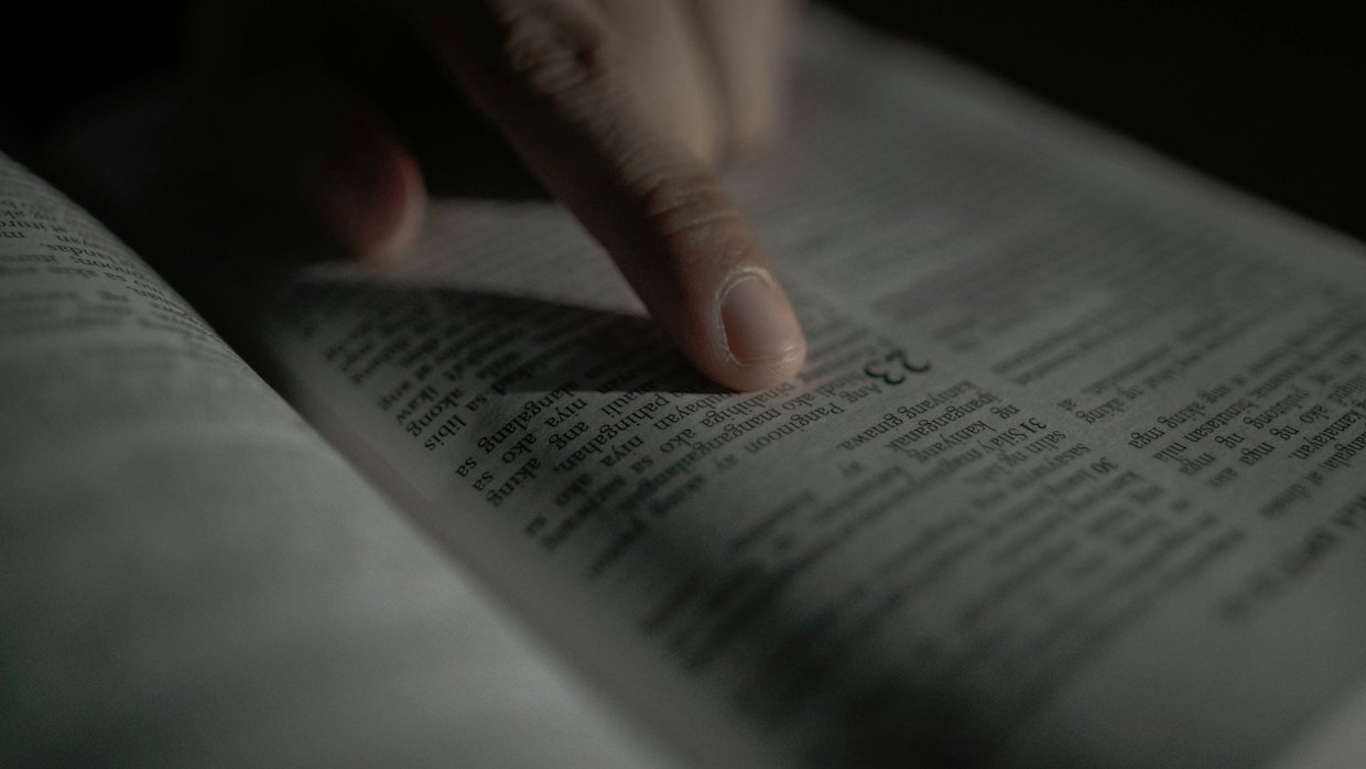A finger marking a place in a book.
