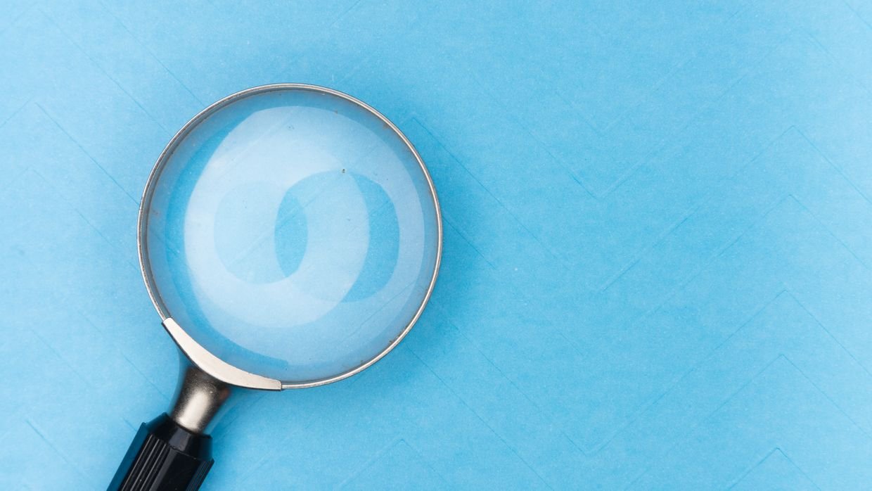 A magnifying glass held over a printed list.