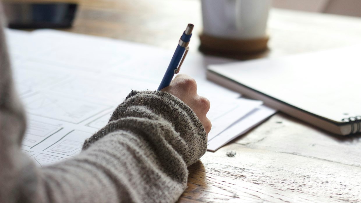 A hand writing notes with a pen.