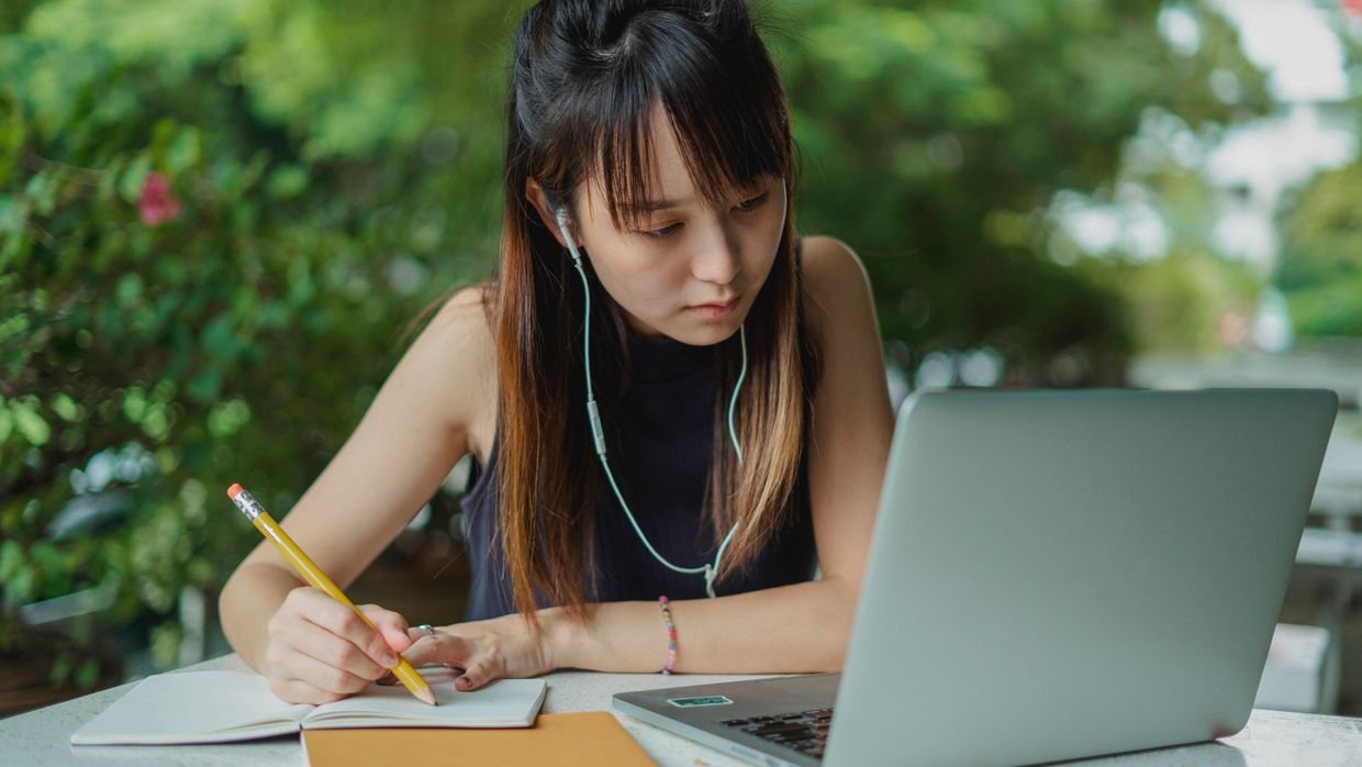 A student taking notes while watching a video, using a summary and the video together.