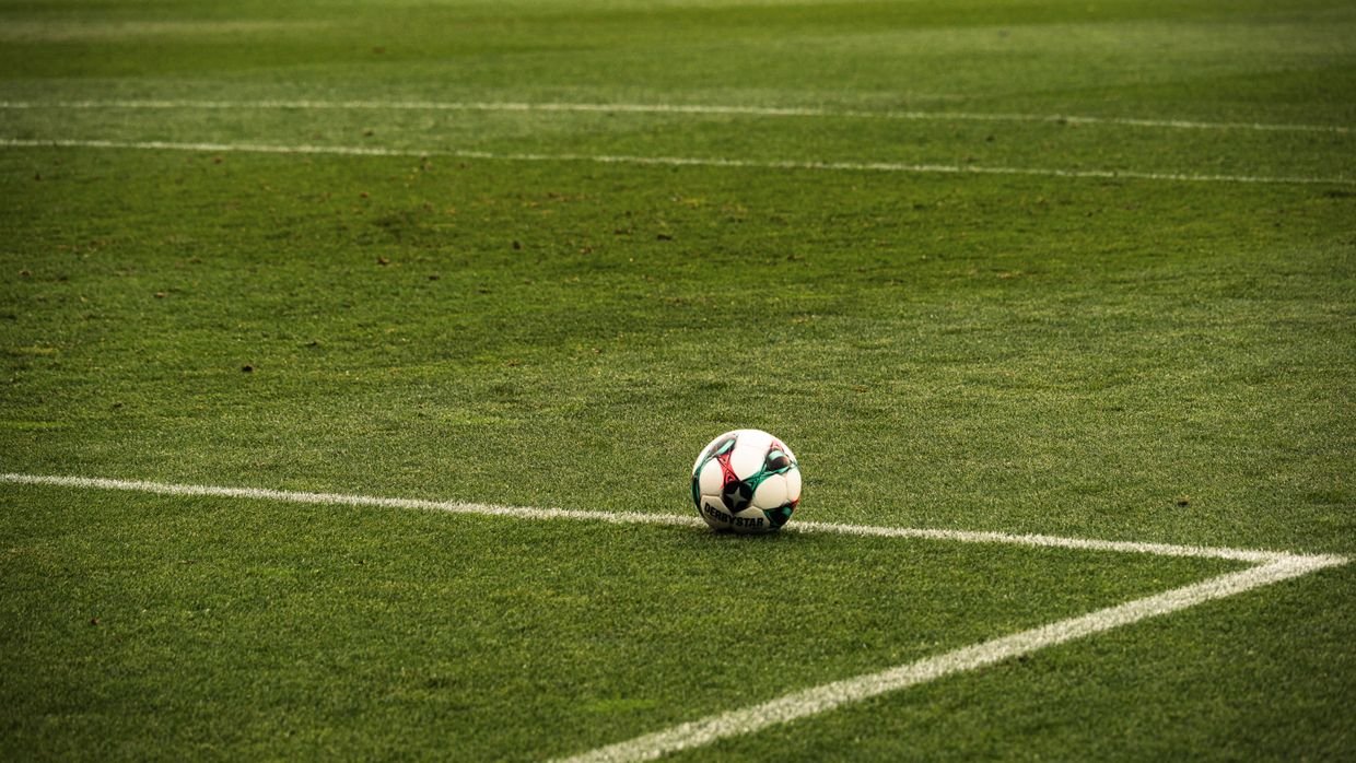A football resting on an empty pitch.