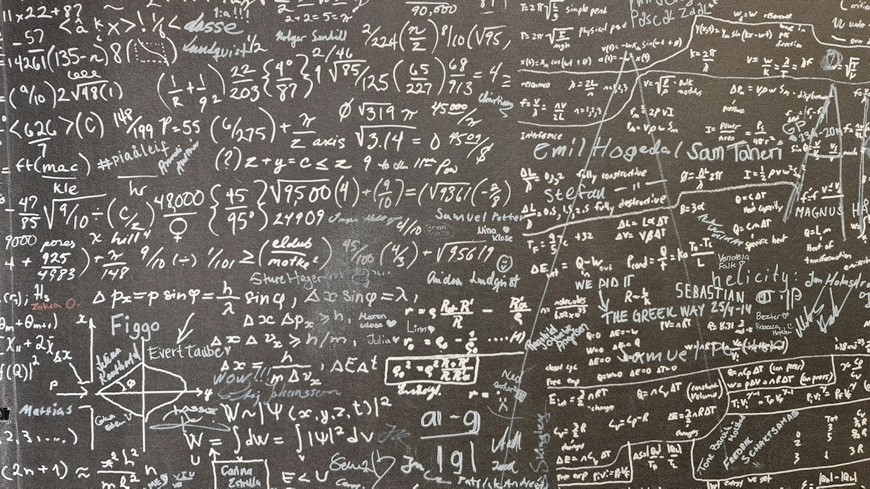 A chalkboard filled with handwritten equations.