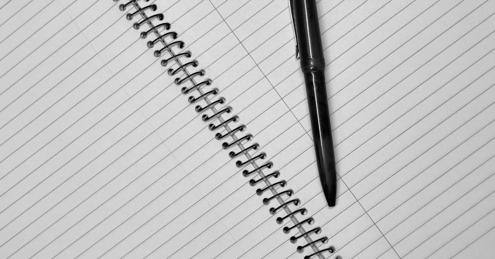 An open notebook at a blank page with a pen resting on it.
