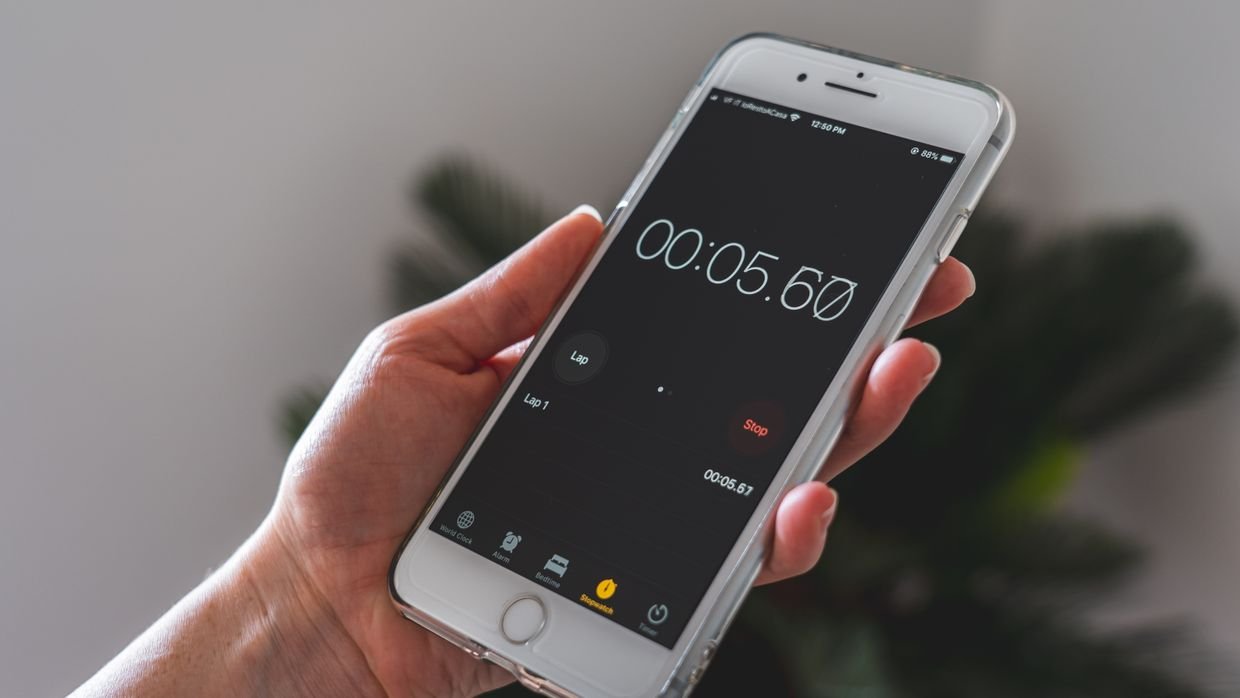 A stopwatch lying beside a phone.