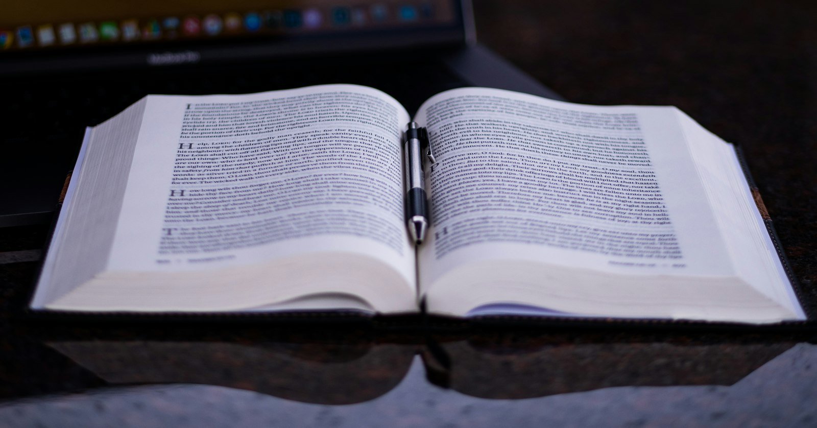 An open dictionary lying beside a laptop.