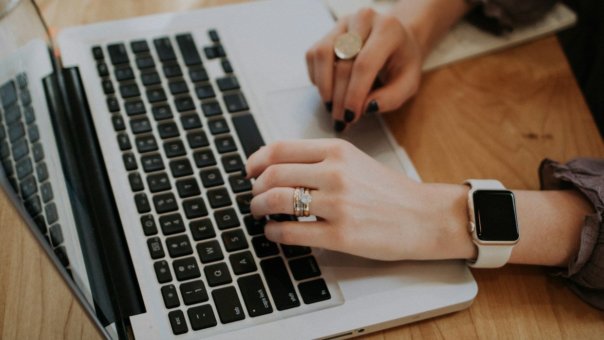 Hands working at a laptop with notes alongside.