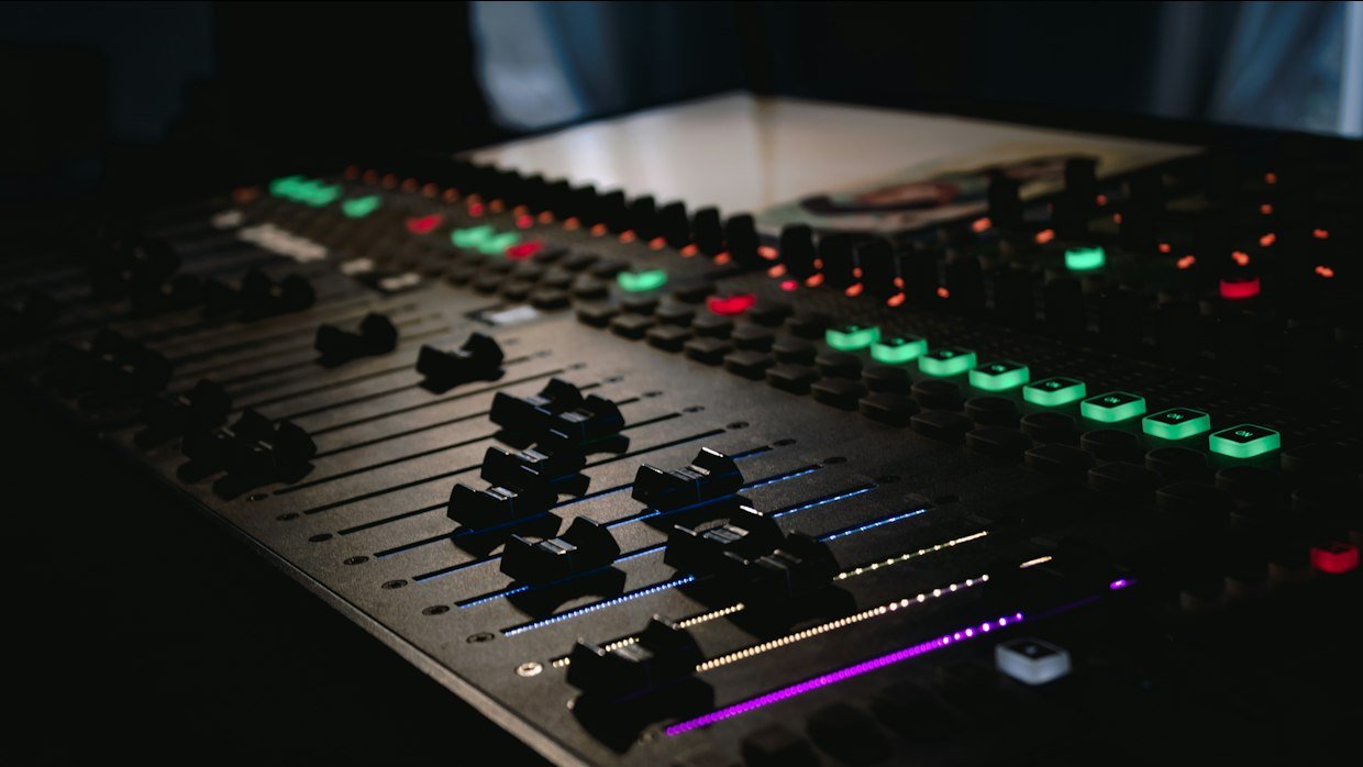 An audio mixing desk with rows of faders.