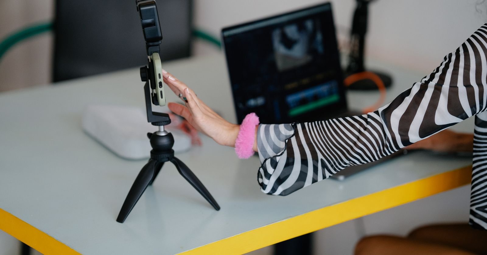A creator’s desk set up for recording, with a microphone and editing timeline on screen.