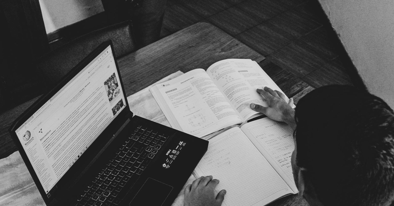 A student working through handwritten notes beside an open laptop.