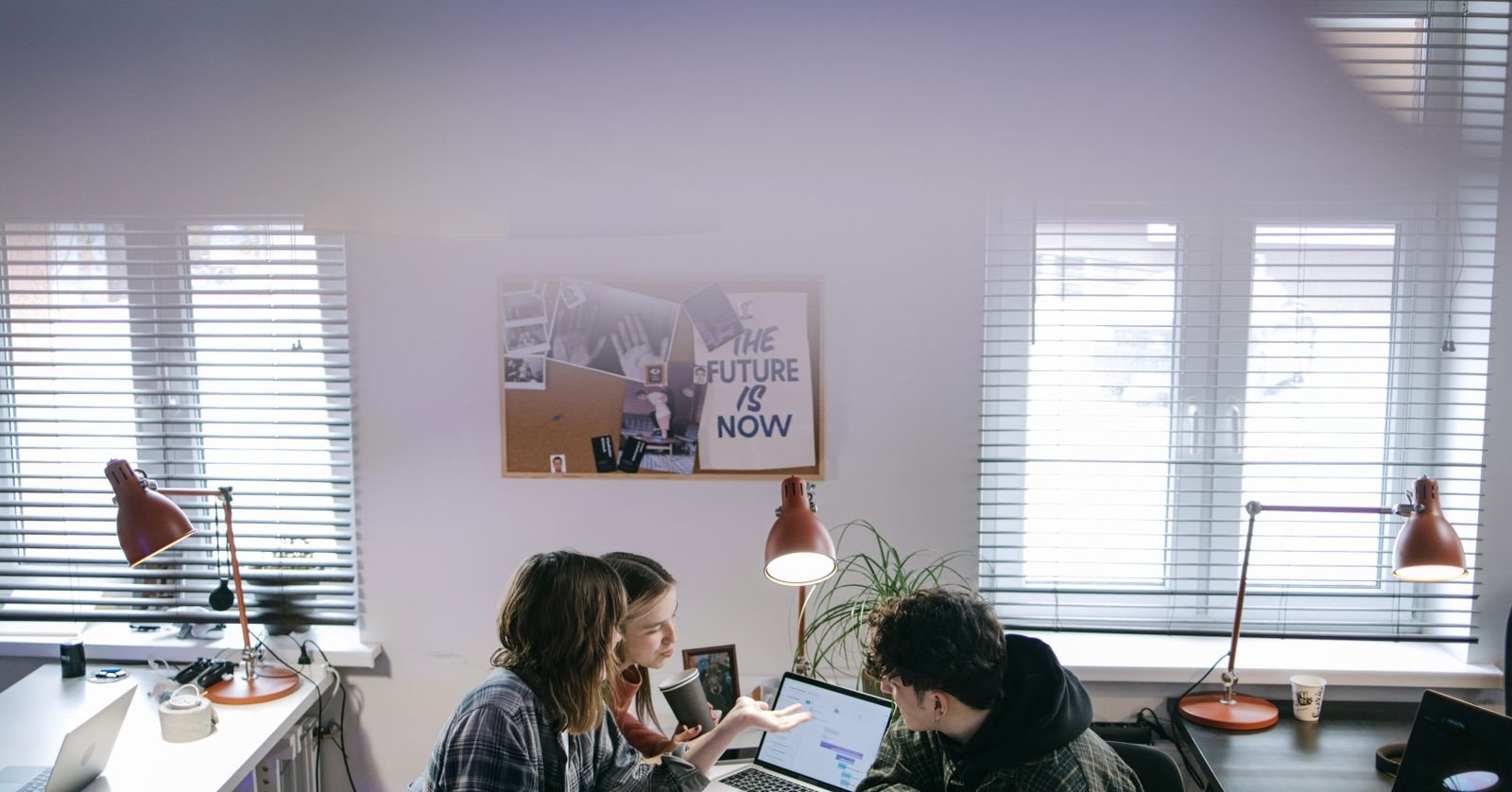A small team around a table, laptops open, mid-discussion.