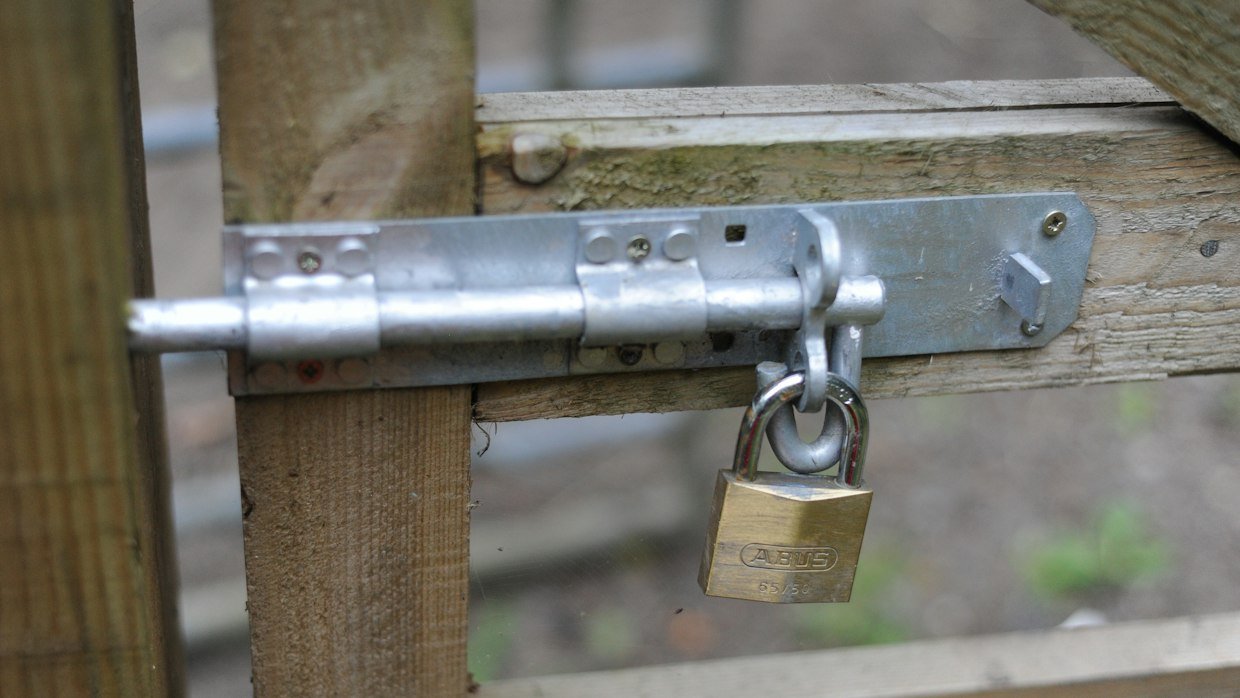 A padlock fastened on a wooden gate.
